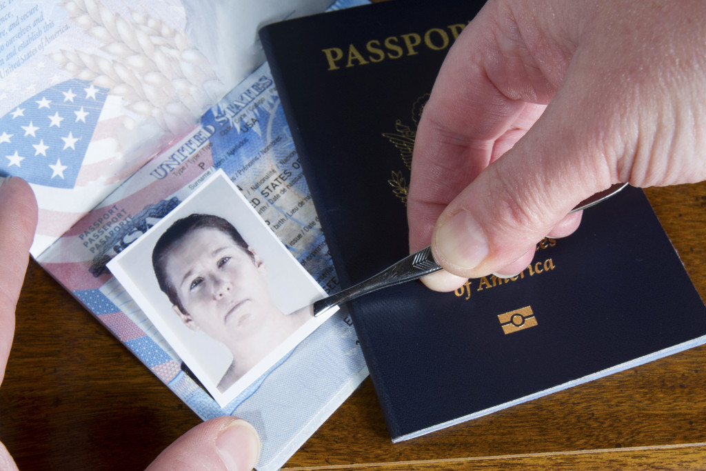 A hand using tweezers to place a photo on top of a passport picture